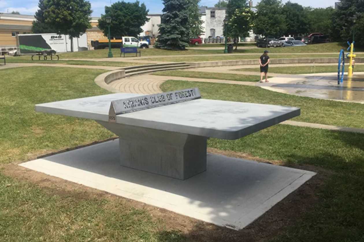 Concrete ping pong table in an open outdoor recreation area beside a field