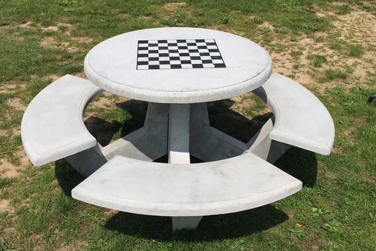 Outdoor chess table with integrated curved seating on a lawn