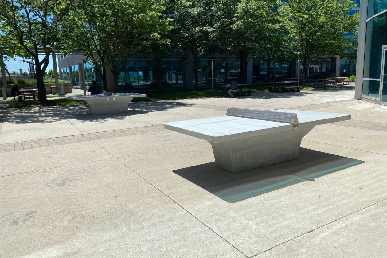 Outdoor ping pong table beside a modern building and landscaped courtyard